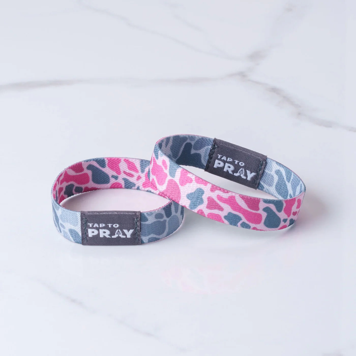 Two wristbands with pink and blue patterns and 'Tap to Pray' text on a white background