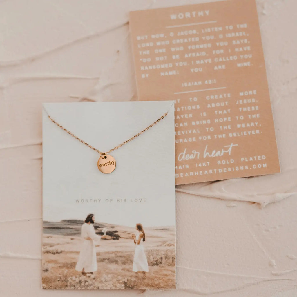 Rose gold necklace with 'worthy' pendant on a card with a scenic photo and text.