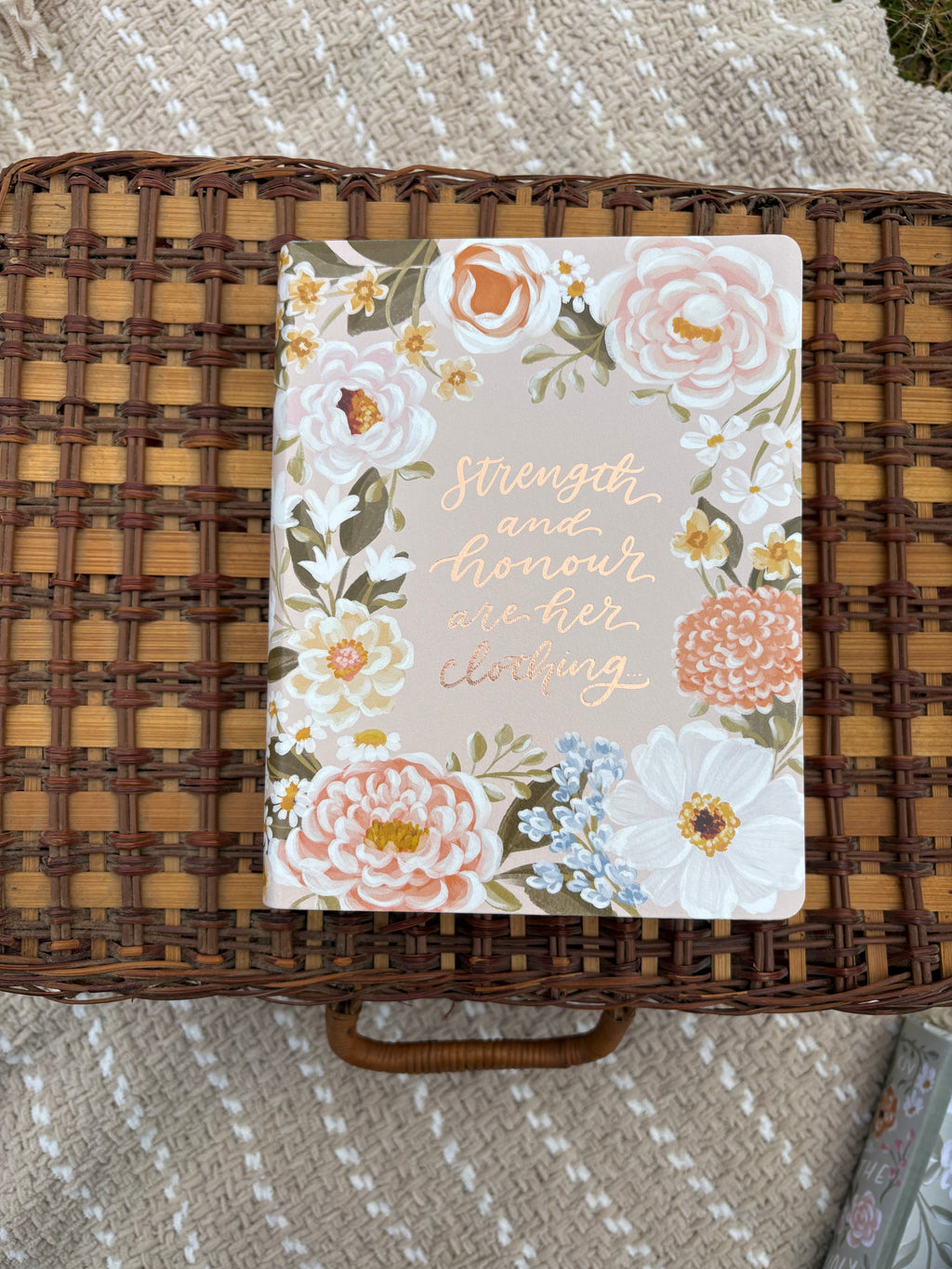 Floral bible with text on a wicker surface with text displayed on the middle of the cover of the front of the Bible
