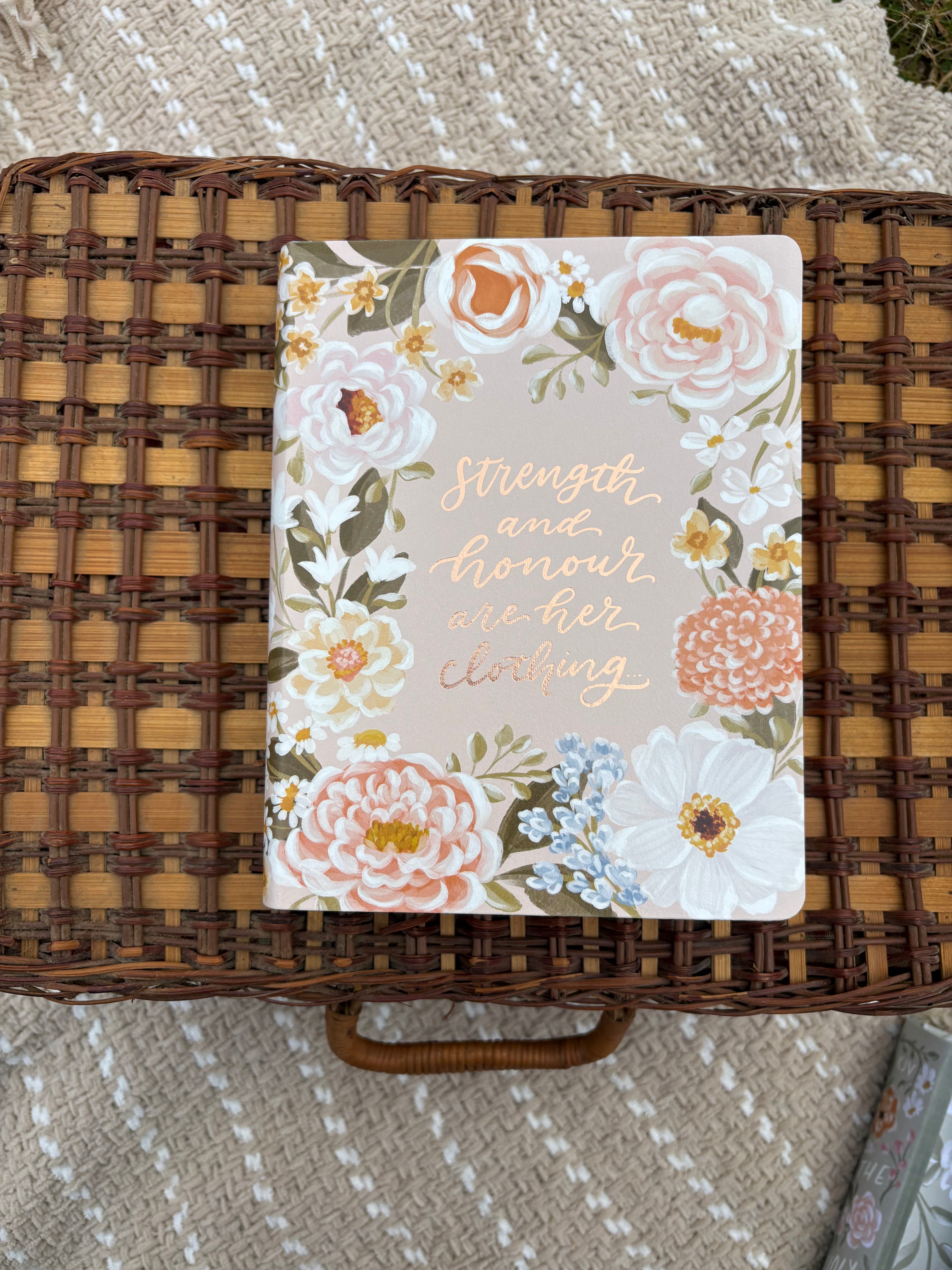 Floral bible with text on a wicker surface with text displayed on the middle of the cover of the front of the Bible