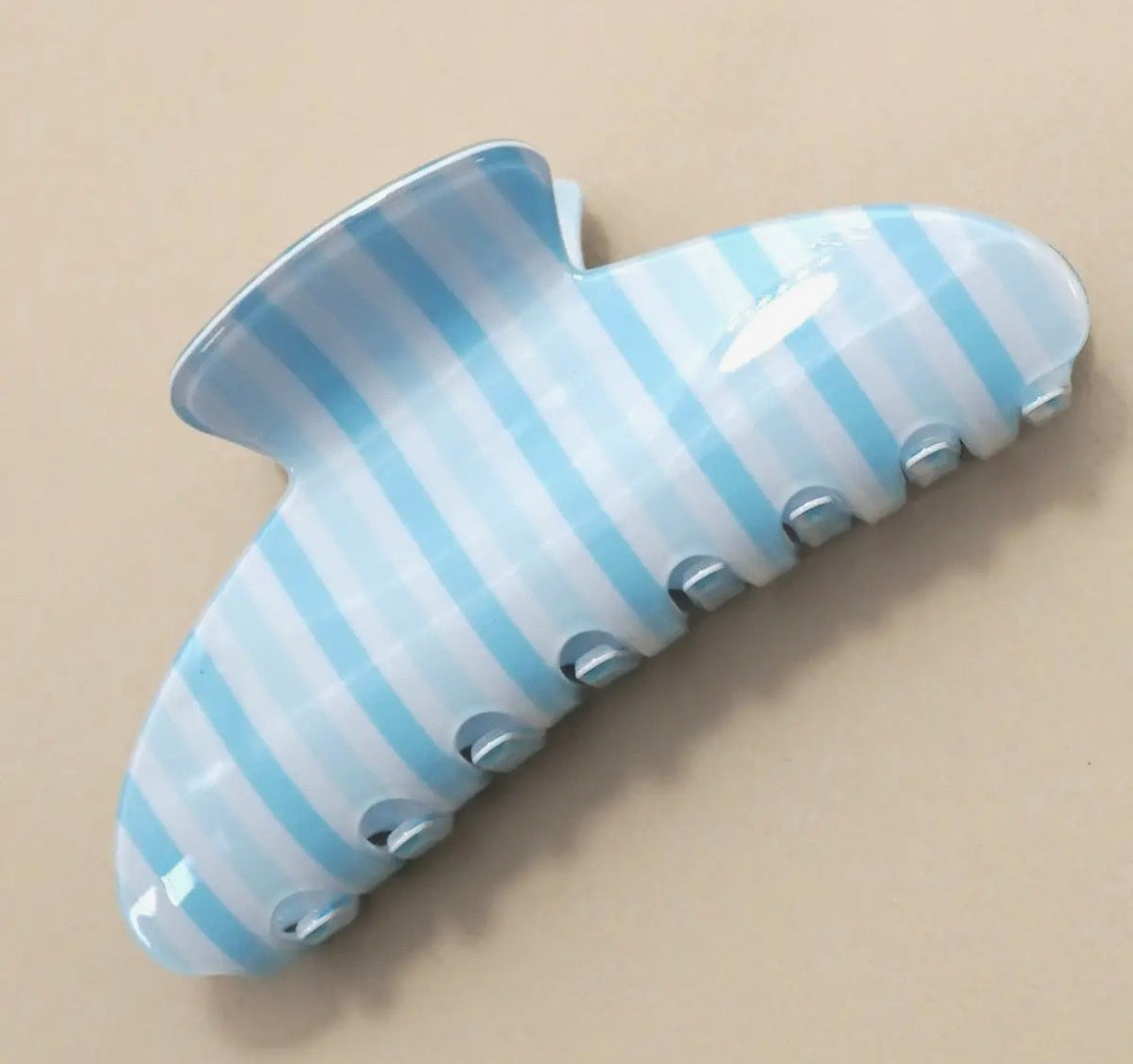 Blue and white striped hair clip on a beige background