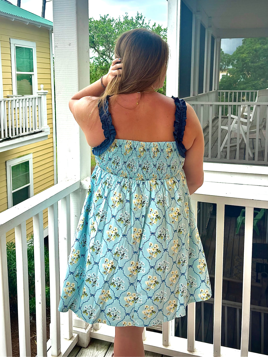 Woman in a floral dress standing on a porch