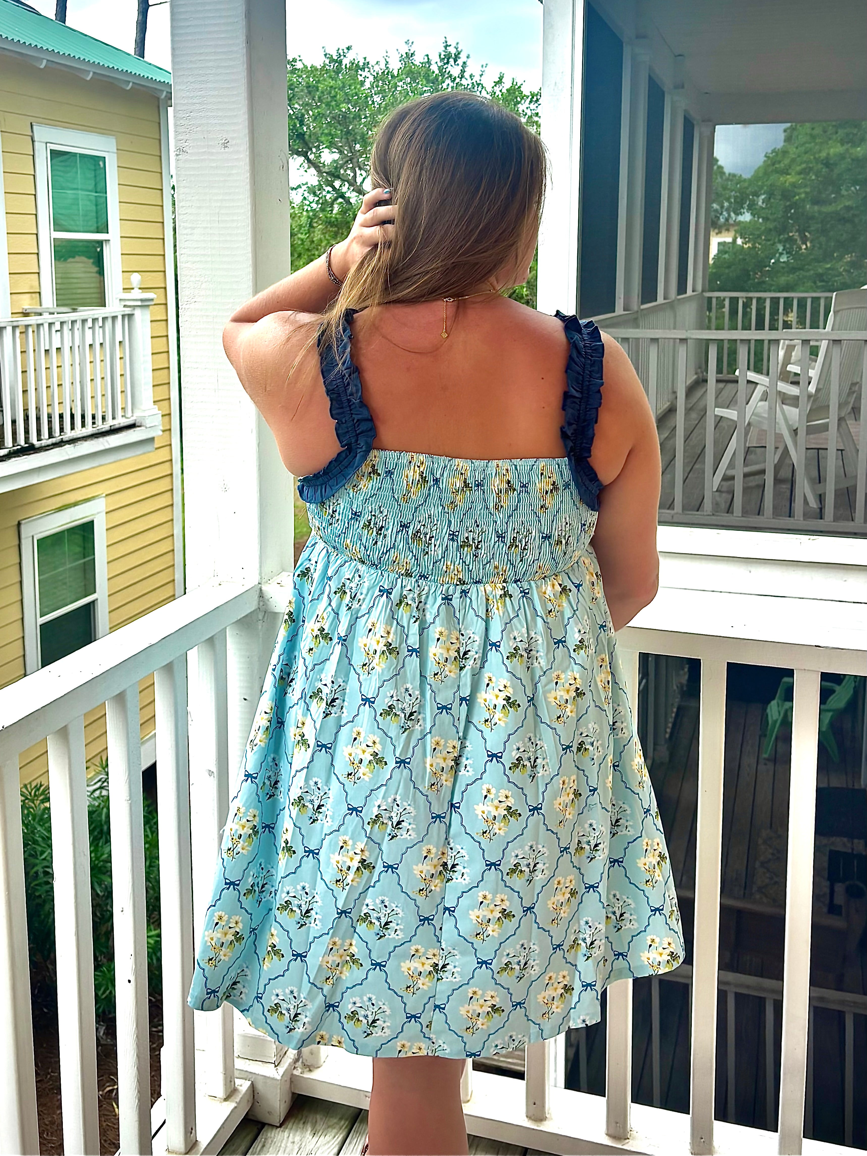 Woman in a floral dress standing on a porch