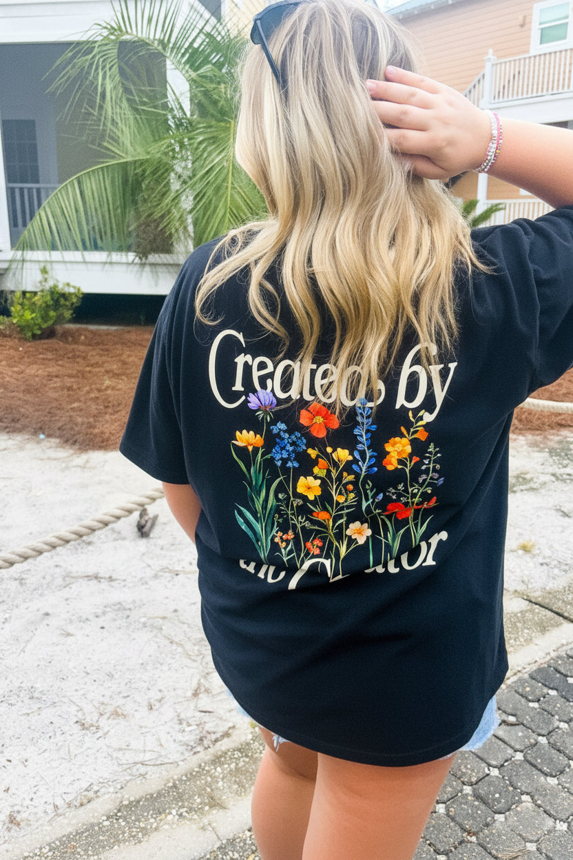 A girl wearing a black t-shirt with text on the back standing outdoors 