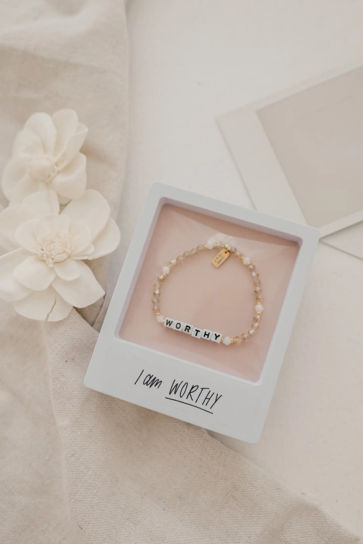 Bracelet with 'I am Worthy' message in a box on a soft beige background
