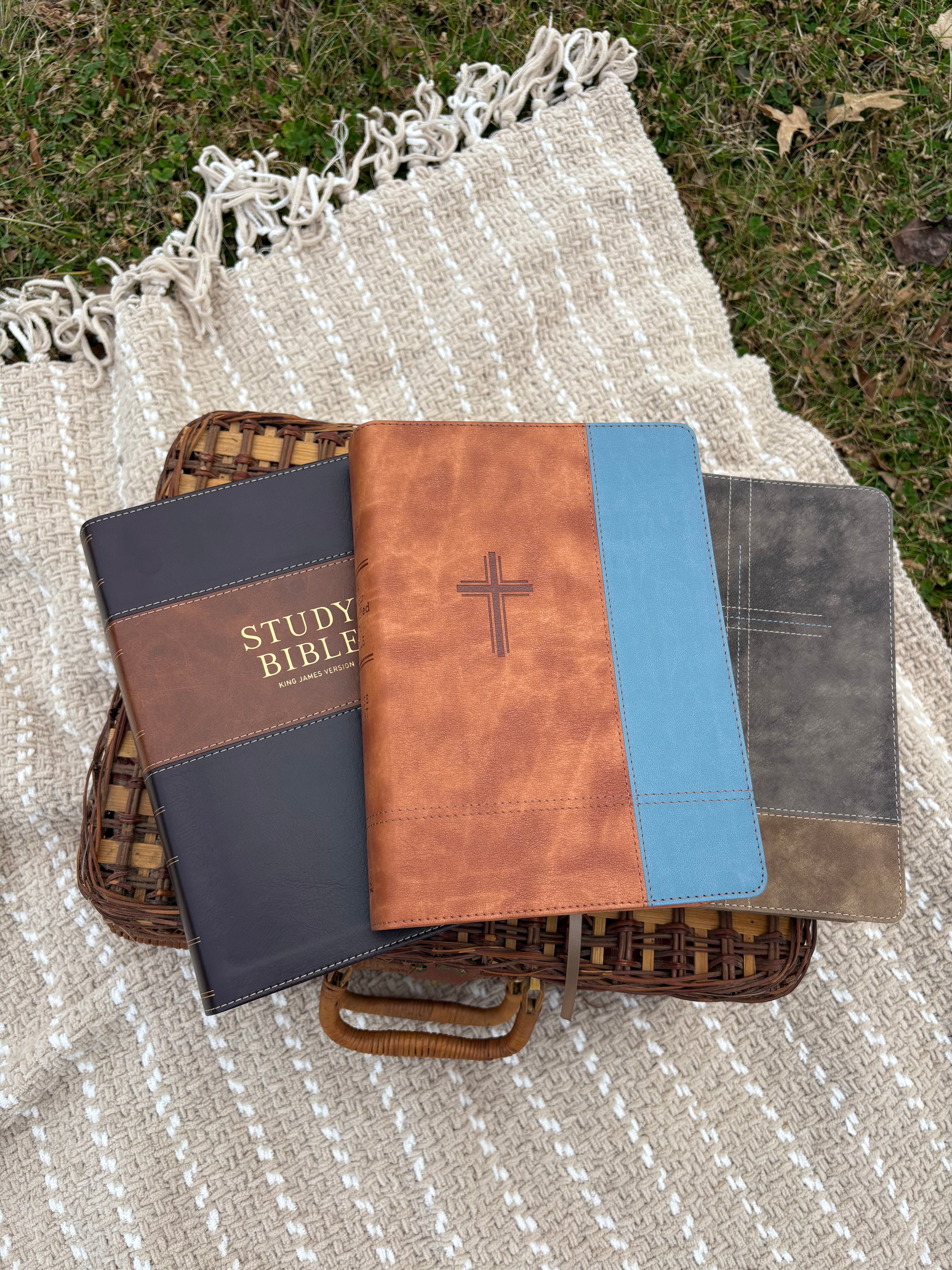 Stack of study bibles on a textured blanket outdoors