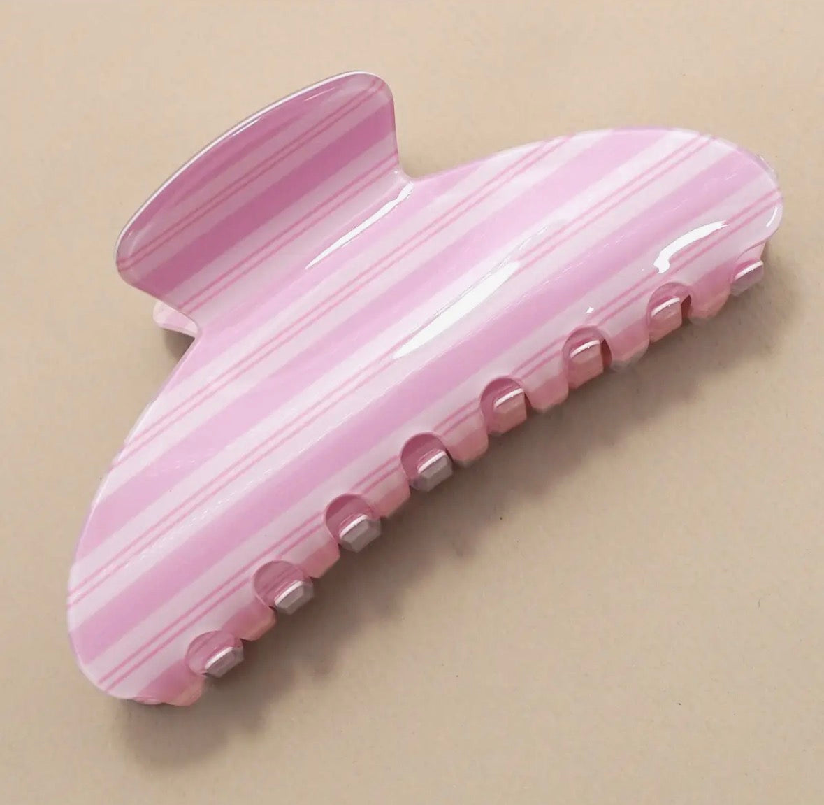 Pink hair clip with a textured surface on a beige background