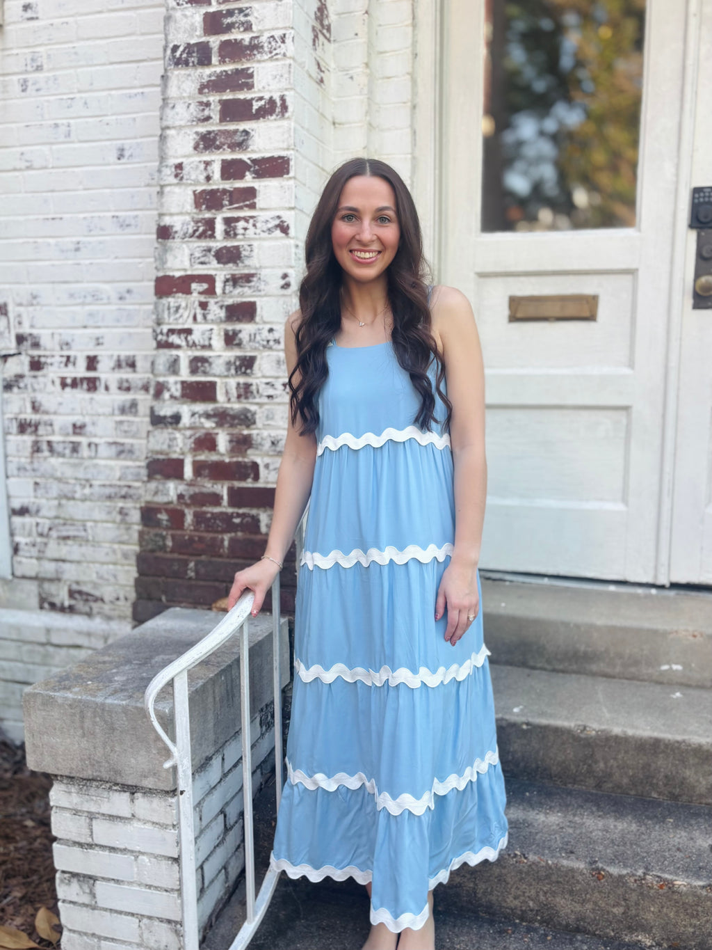 Woman in a light blue dress with white trim standing on steps outside a church.