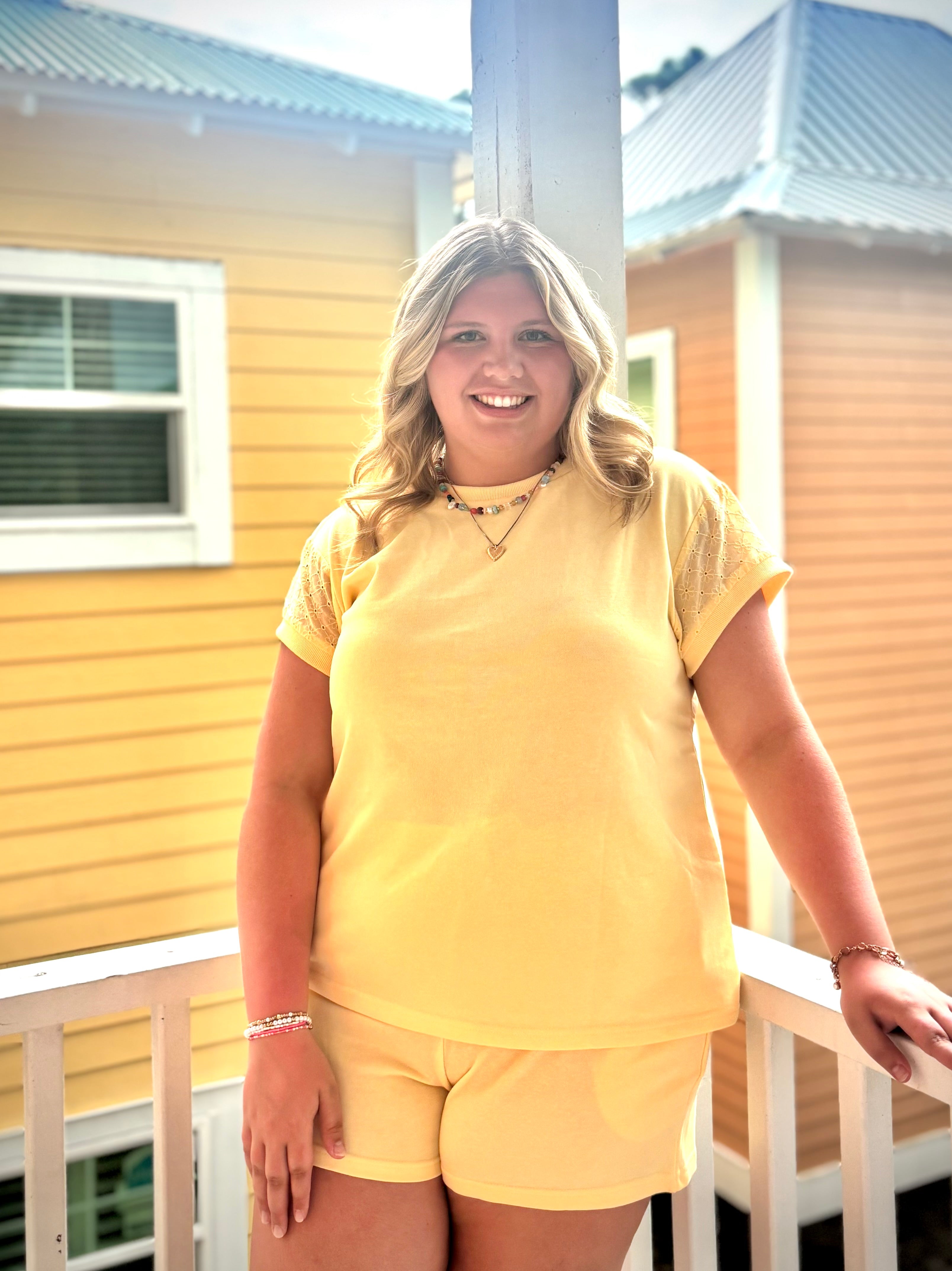Woman in a yellow outfit standing on a porch with a house in the background