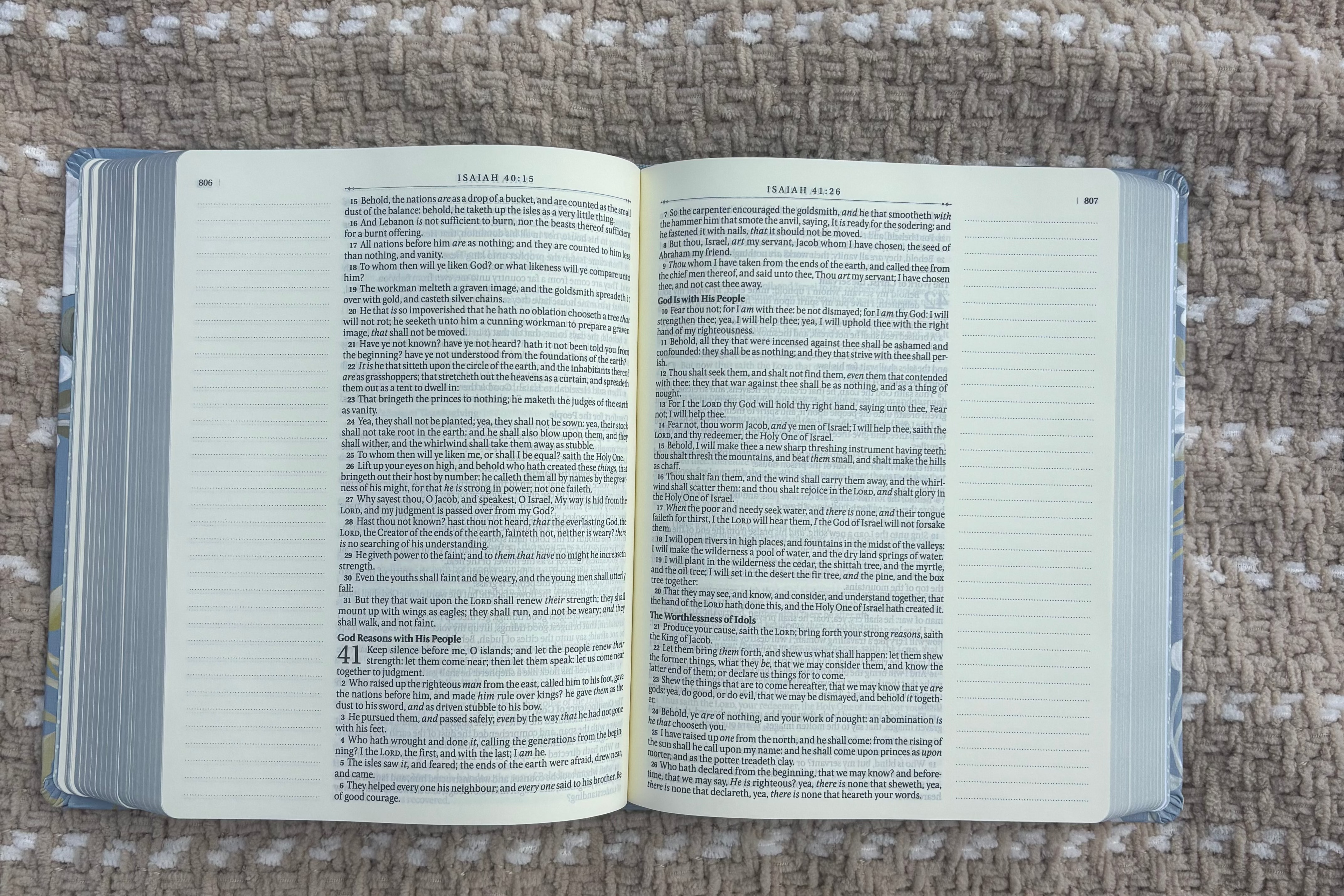 An open Bible with text on the pages laying on a beige blanket outdoors