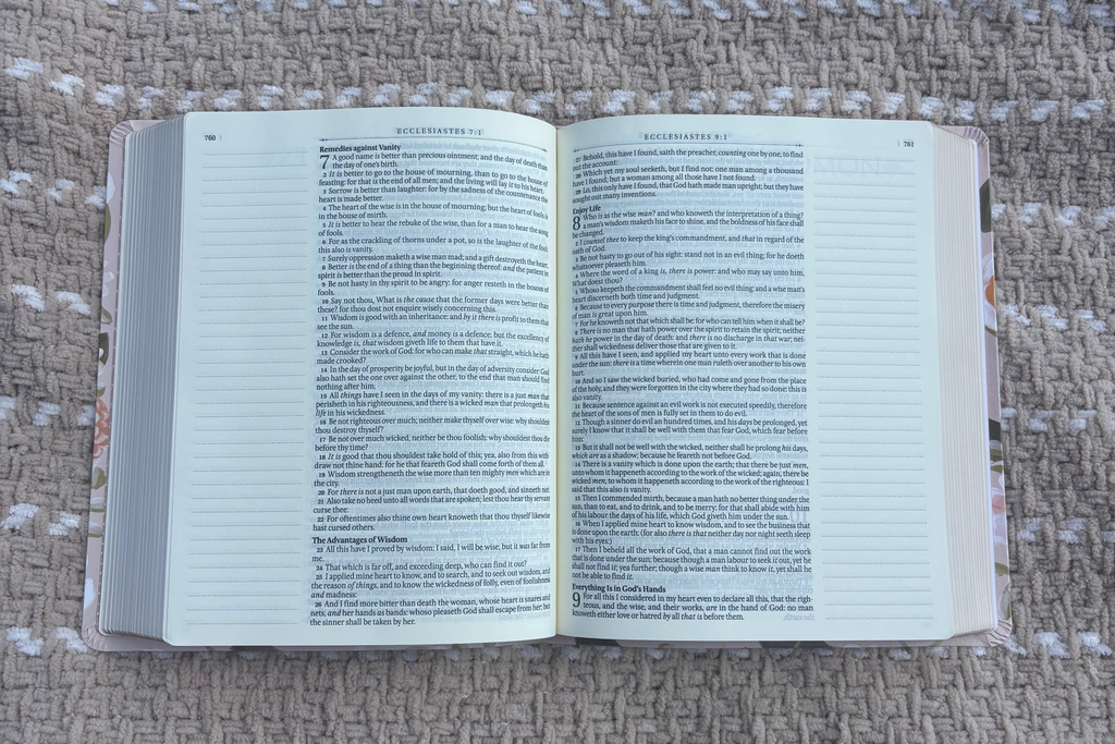 Open Bible with text on the pages laying on a beige blanket outdoors