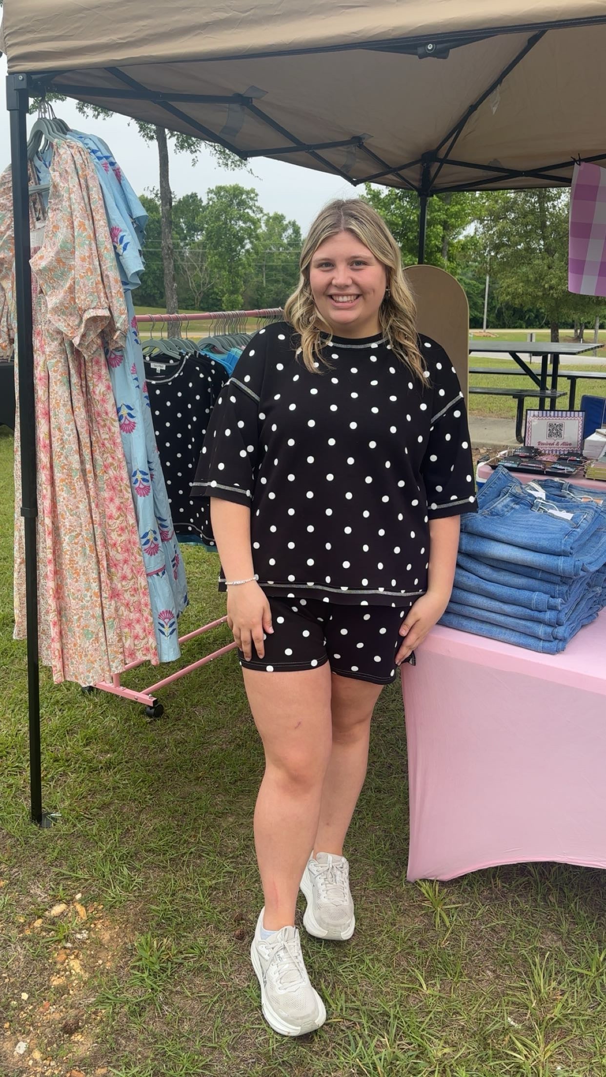 Woman standing under a tent with clothing items displayed around her