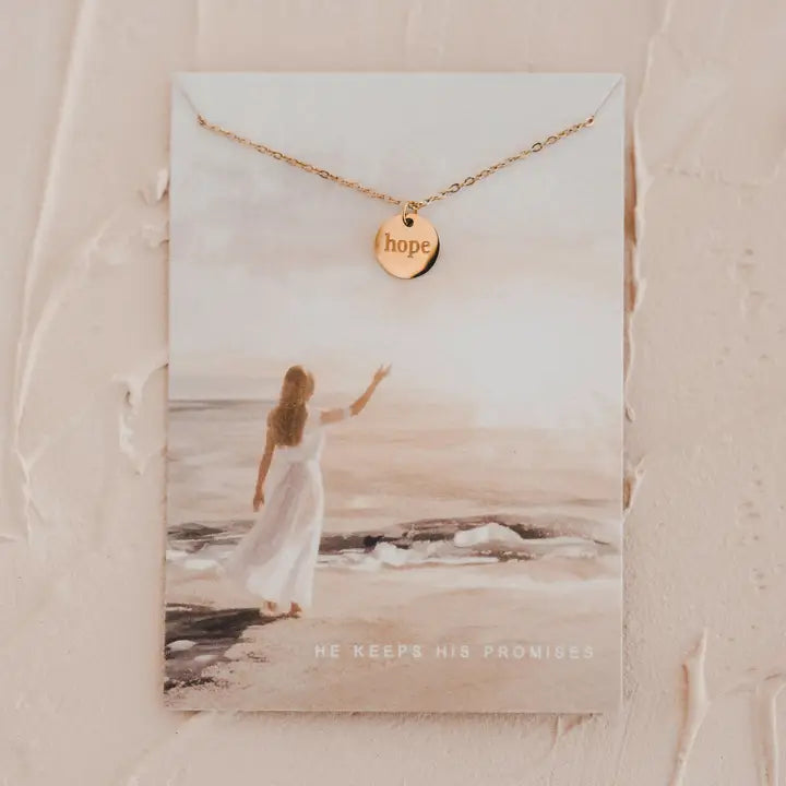 Gold necklace with 'hope' pendant on a card featuring a beach scene