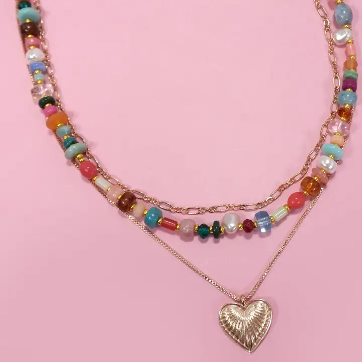 Multicolored beaded necklace with a heart pendant on a pink background
