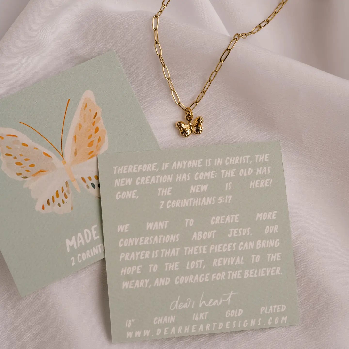Gold necklace with butterfly pendant on a green card with text